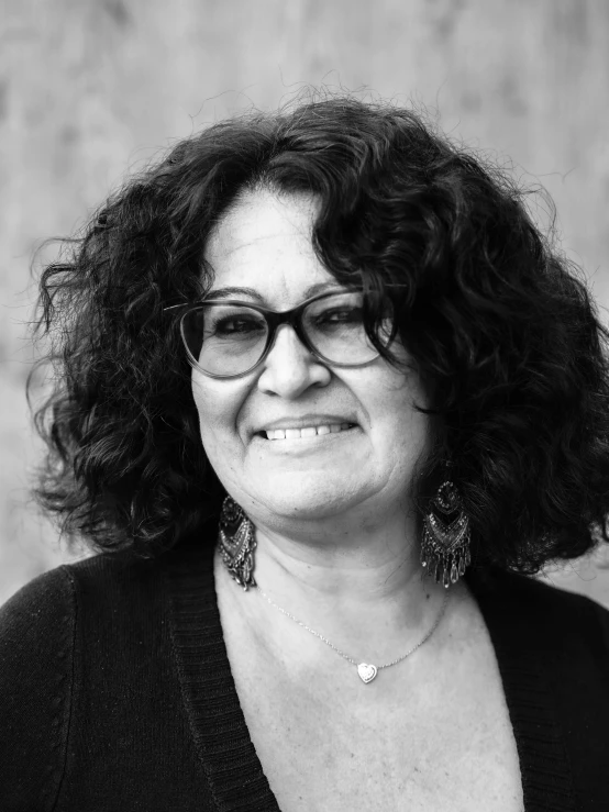 a woman wearing glasses with curly hair and earrings
