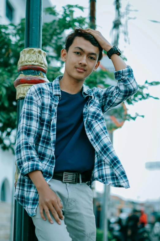 a man standing next to a pole wearing a blue shirt