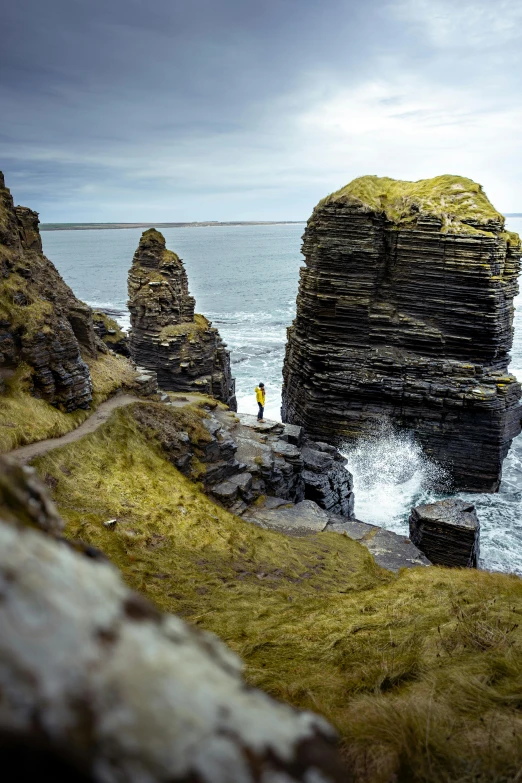 a lone man standing near the sea, by a cliff