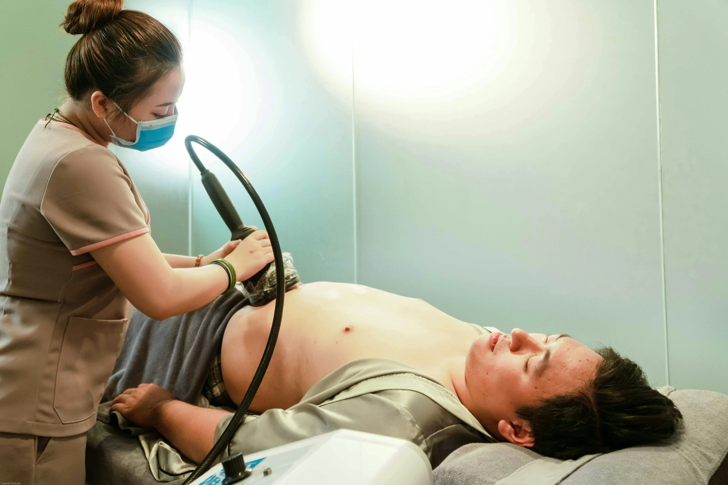 a person laying on a hospital bed near a monitor