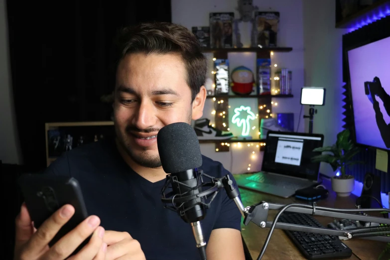 a man looking at his phone as he sings into a microphone