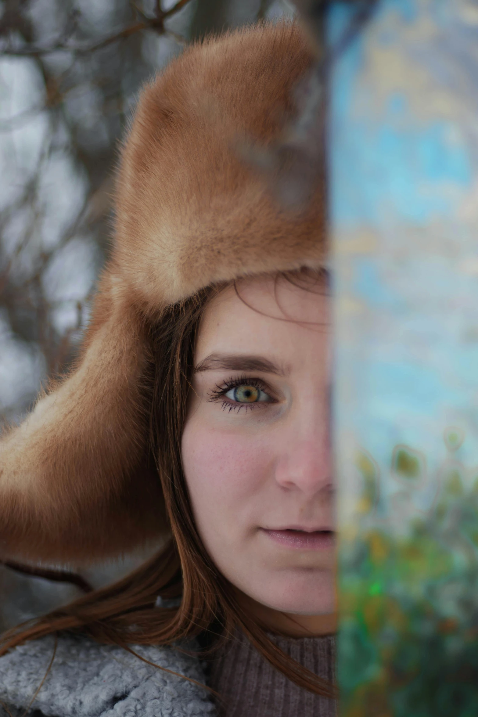 a girl wearing a fur hat looks into the distance