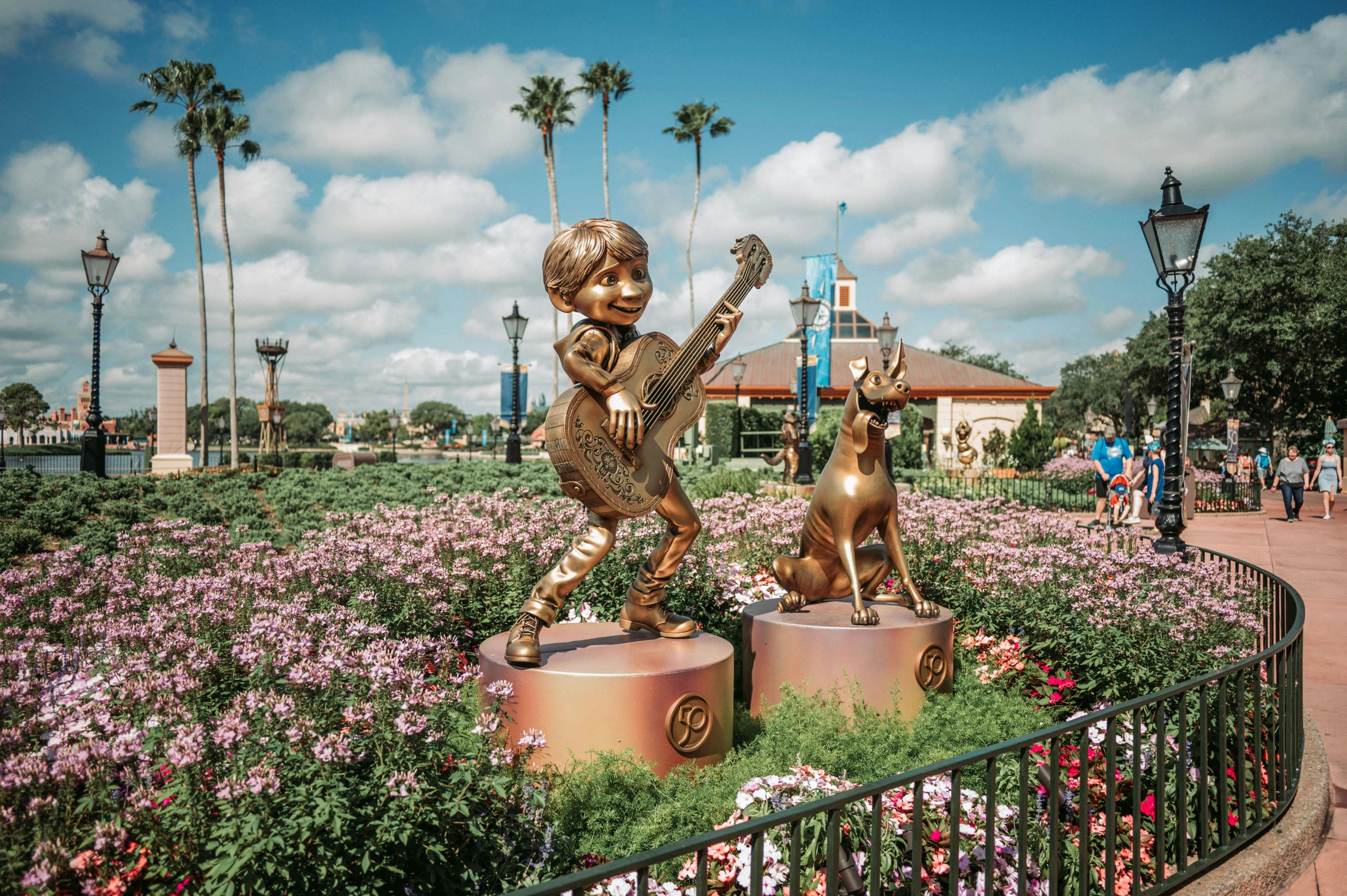 a statue of a boy playing the guitar in a field of flowers