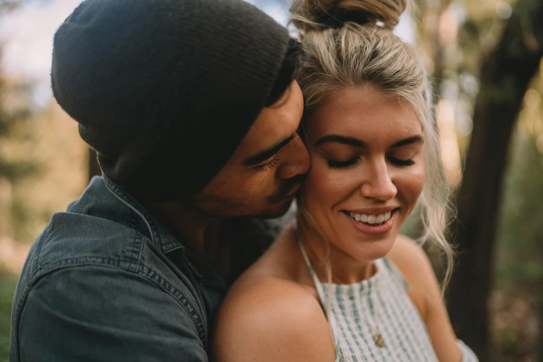 an attractive blonde young man is hugging an attractive woman with headphones