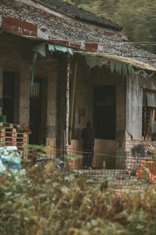 an old, run down house with a man standing outside