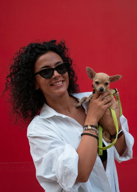 a woman wearing sunglasses and holding a small dog