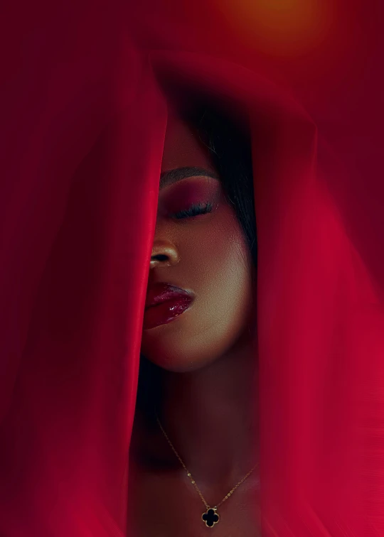 a woman is hiding behind a blanket with the red background