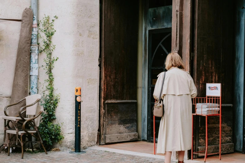 a woman in a white coat standing outside of a building