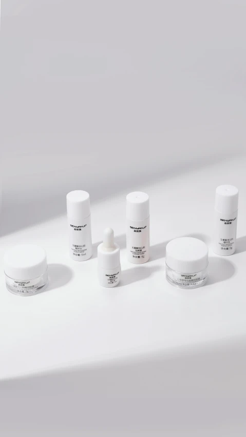 five white cosmetic containers on top of a white table