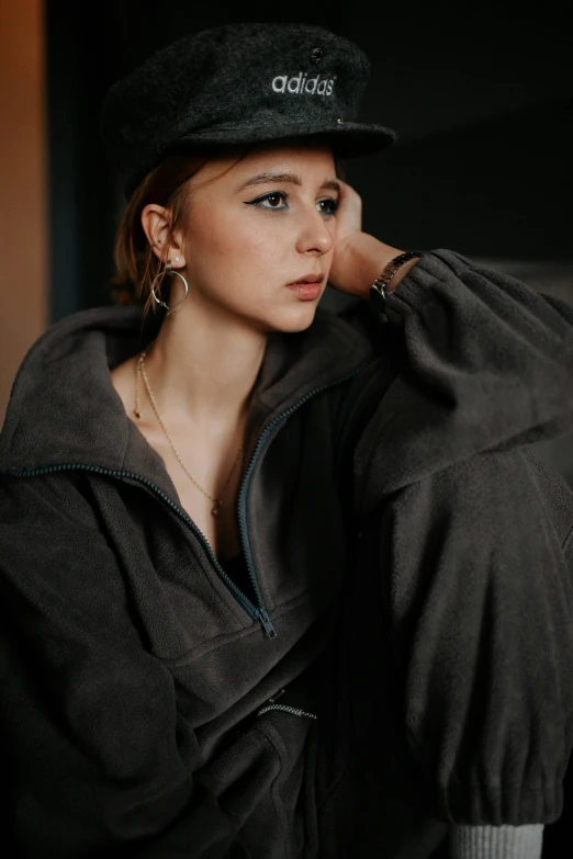 a woman with a hat is leaning up against the wall