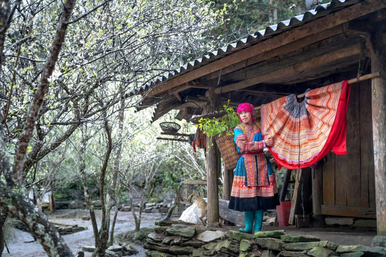 woman wearing an oriental costume standing next to a wooden building