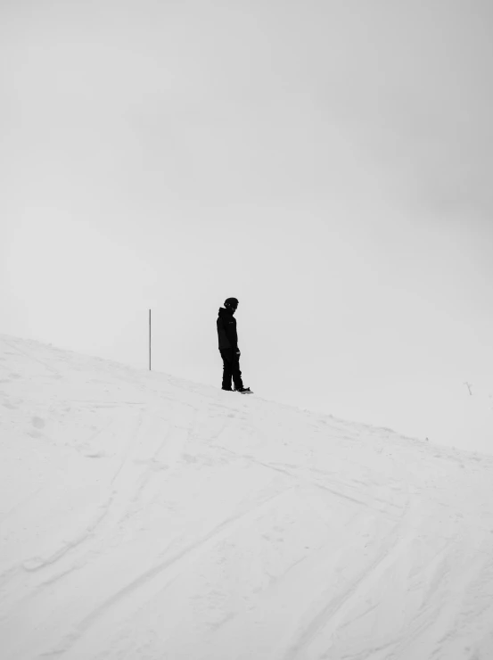 a snowboarder in a black coat is walking on the snow