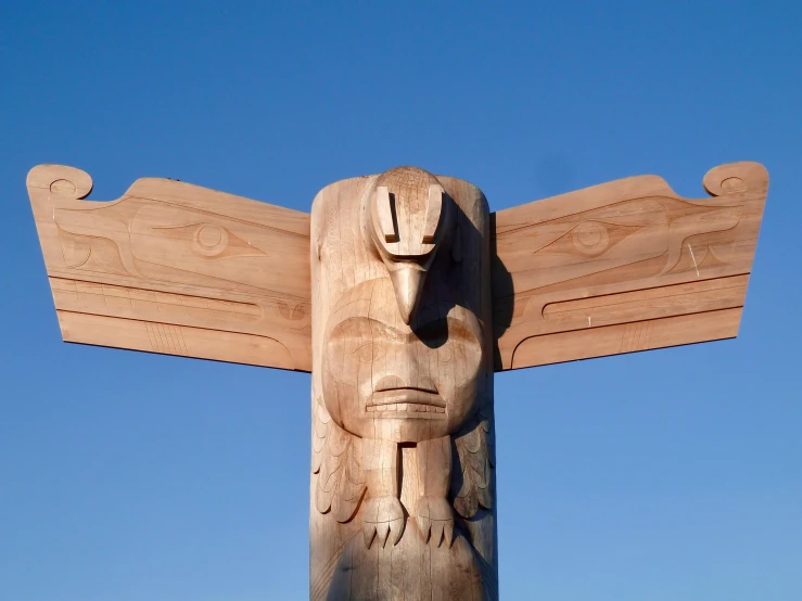 the sculpture is made out of wood with a bird head and large wings