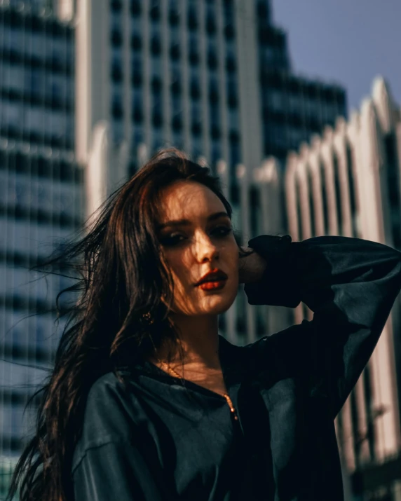 a woman posing for a po with large buildings in the background