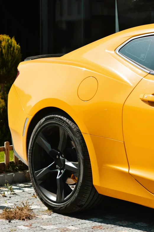the rear end of a yellow sports car with shiny black wheels