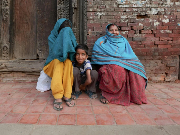 a woman and a child sit on a brick floor