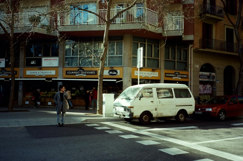 a white van driving down a street past tall buildings