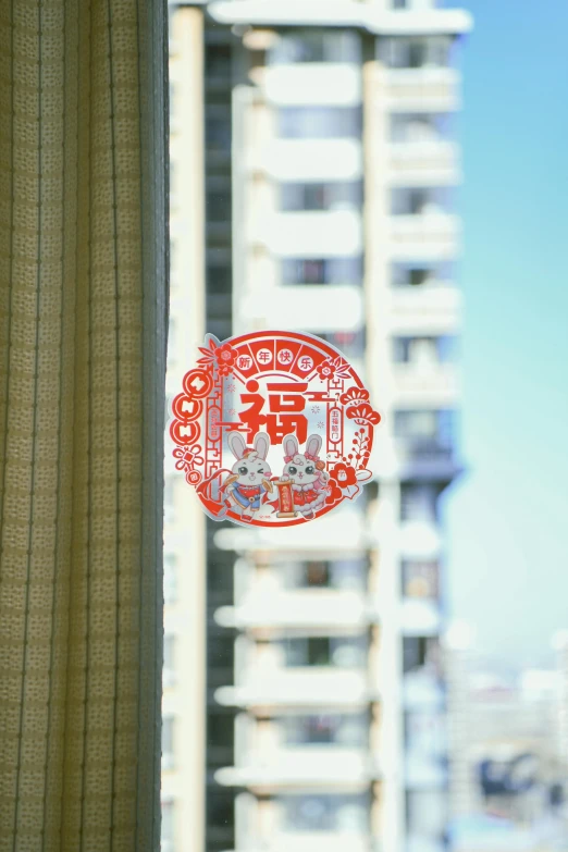a red and white sticker hangs on a curtain