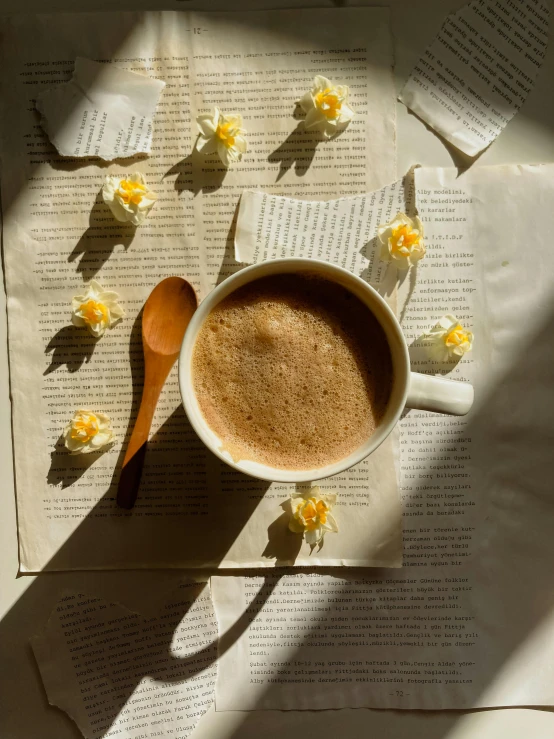 a cup of coffee sitting on top of a paper next to flowers