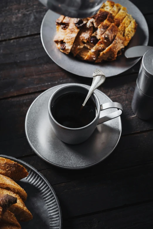 there are two silver plates and spoons sitting on the table