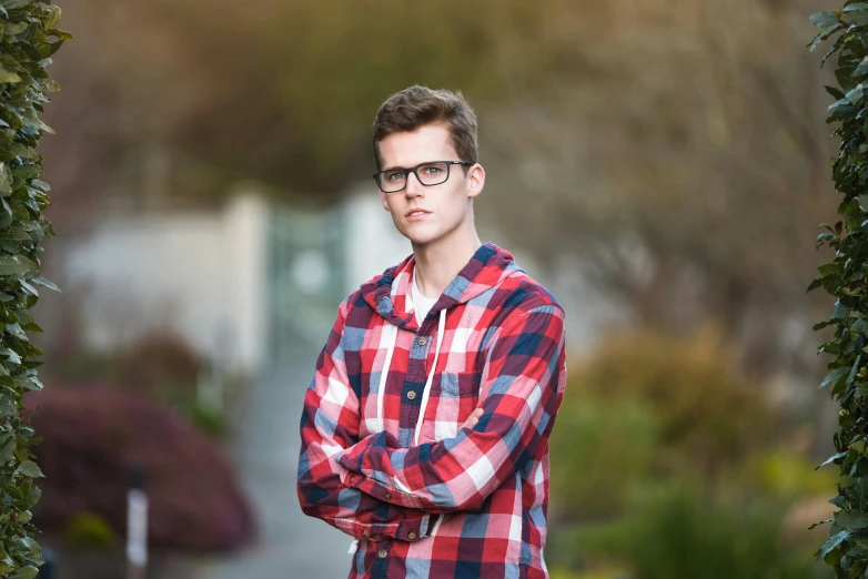 a young man in glasses is standing outdoors