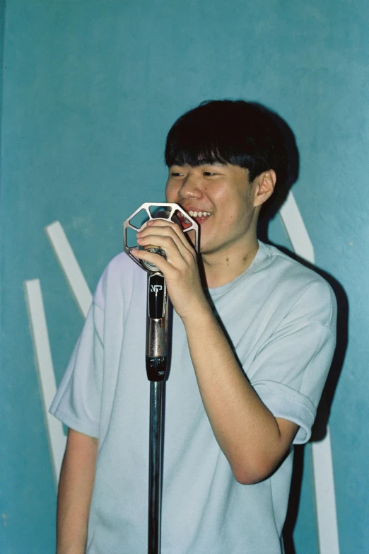 a smiling person standing in front of a microphone