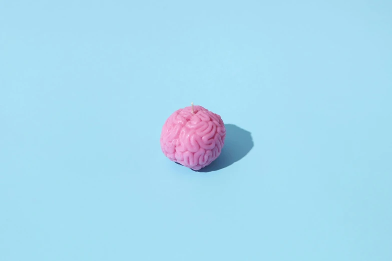 a ball of pink plastic in candy on a blue surface