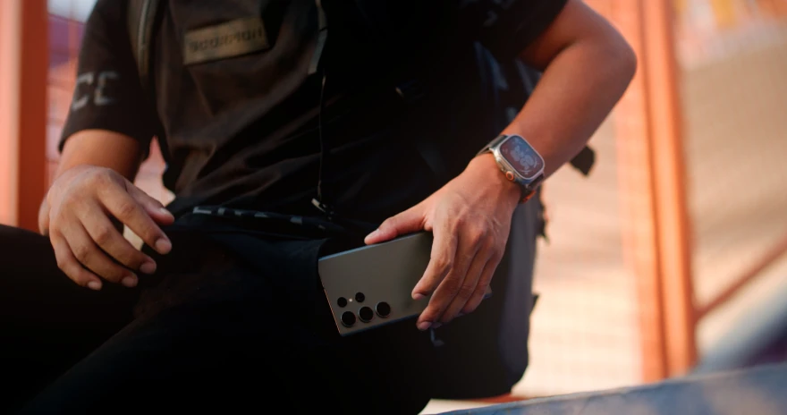 a man sitting down while holding an electronic device