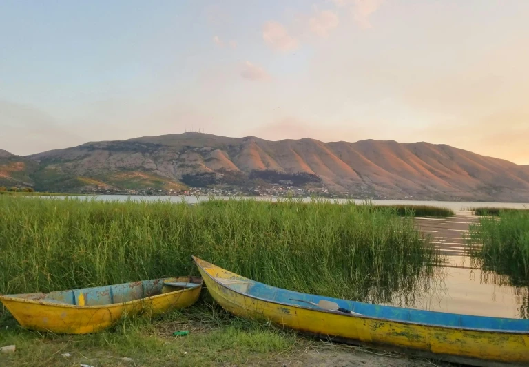 some boats are resting on the shore near some water