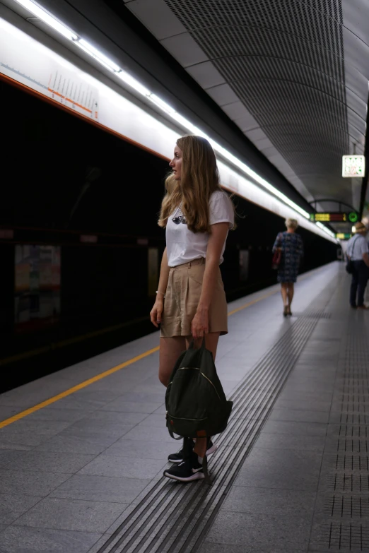 a young lady is standing alone in a train station