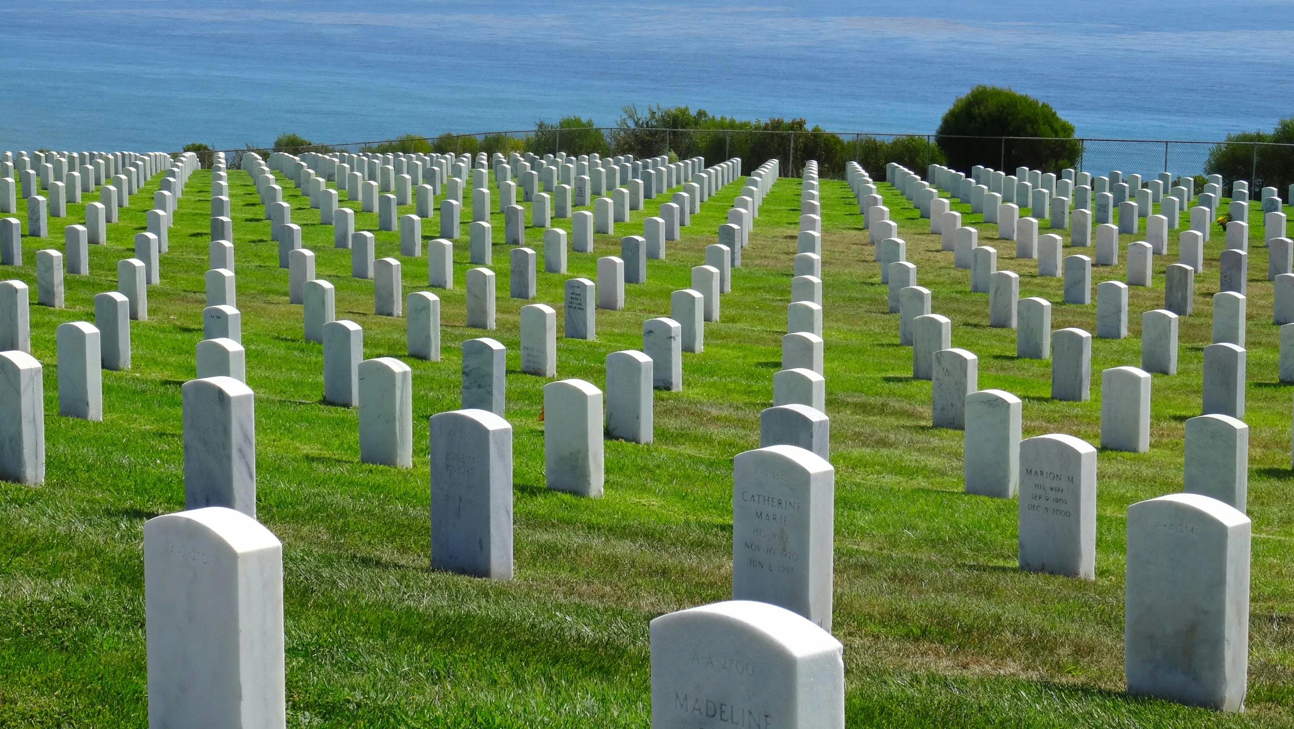 a field of headstones in front of the ocean