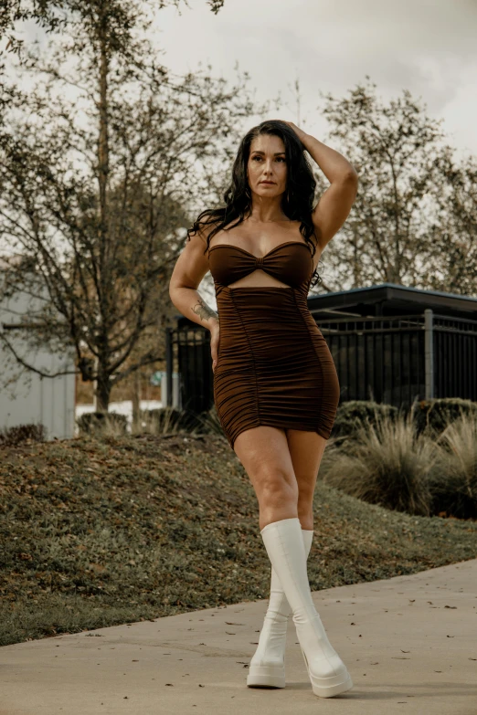 a woman in short brown dress walking across sidewalk