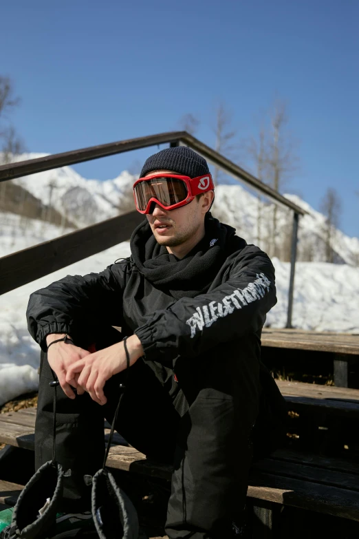 a man wearing ski goggles sitting on a wooden bench