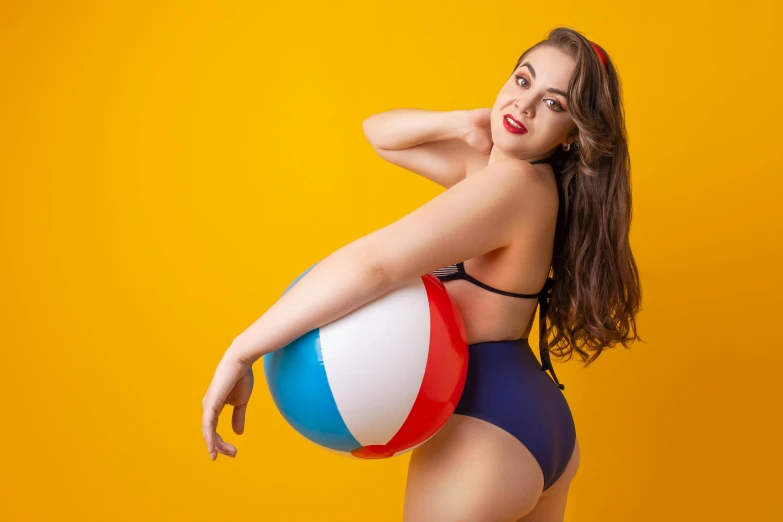 a woman holding a colorful ball wearing a bikini