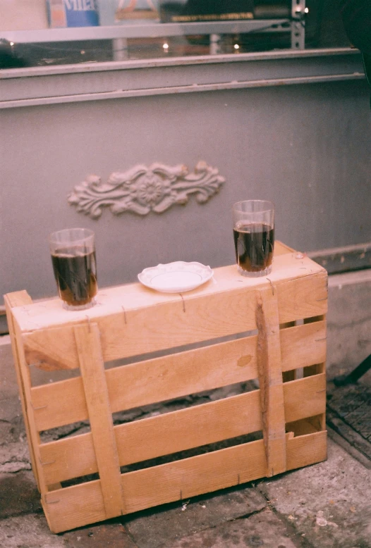 two glasses of beer sit on top of a wooden crate