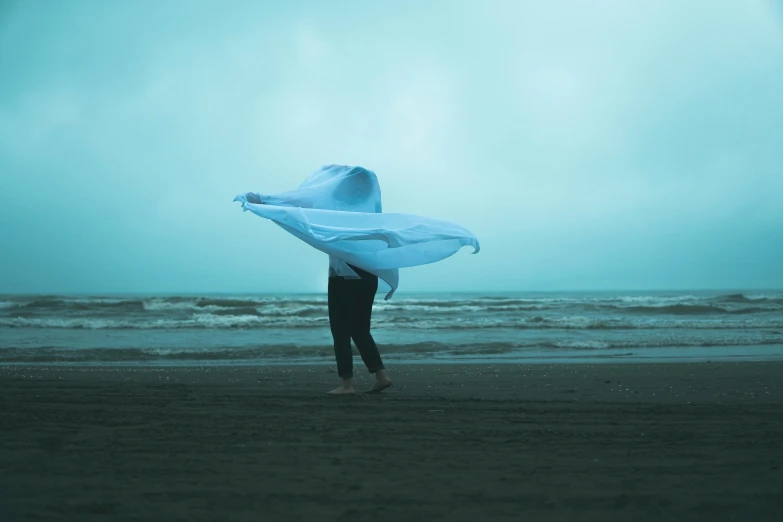 a person walking on a beach holding up an umbrella