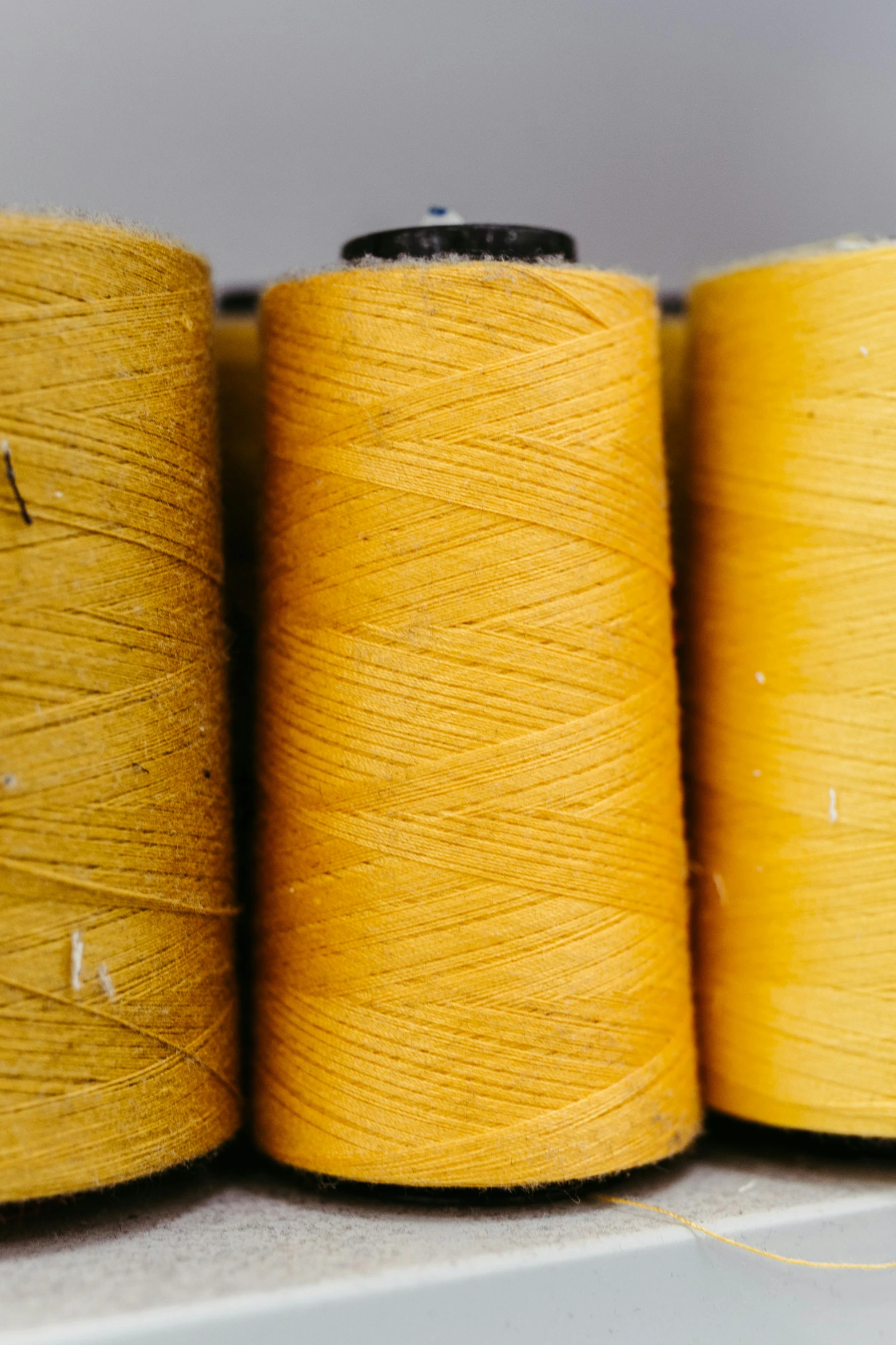 yellow spools of thread on a table next to two ends of yellow string