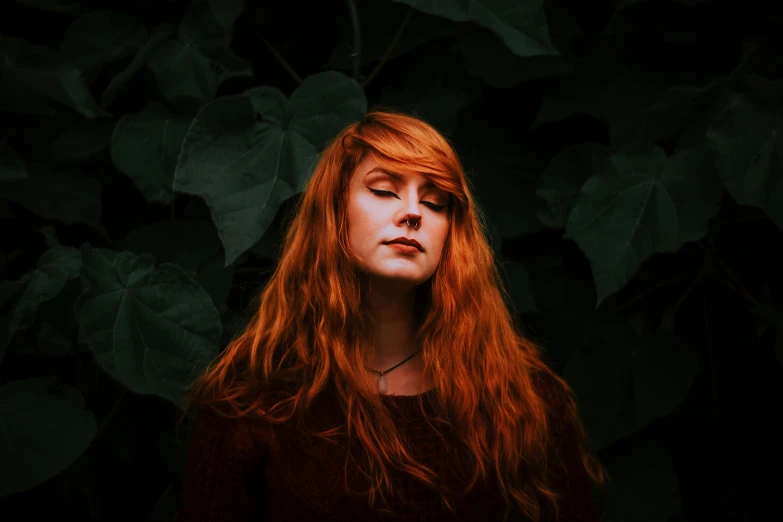 a woman with long hair stands in front of a tree