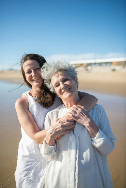 an old woman hugging another women on the beach