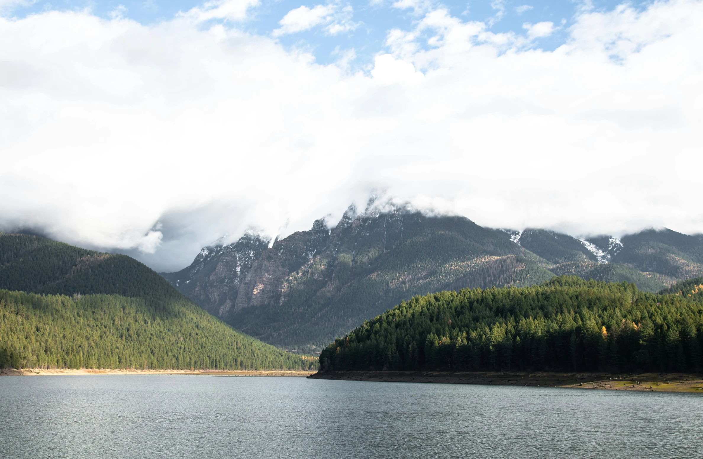 a mountain range with lake and trees below