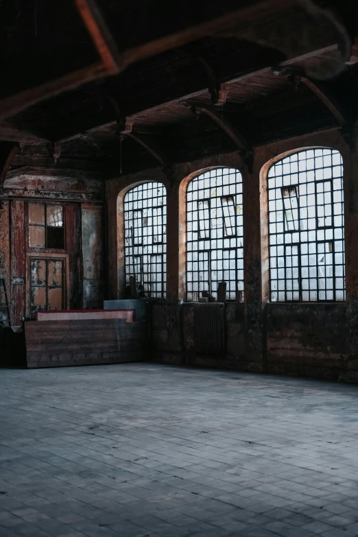 a large empty room with three windows and a wooden bench