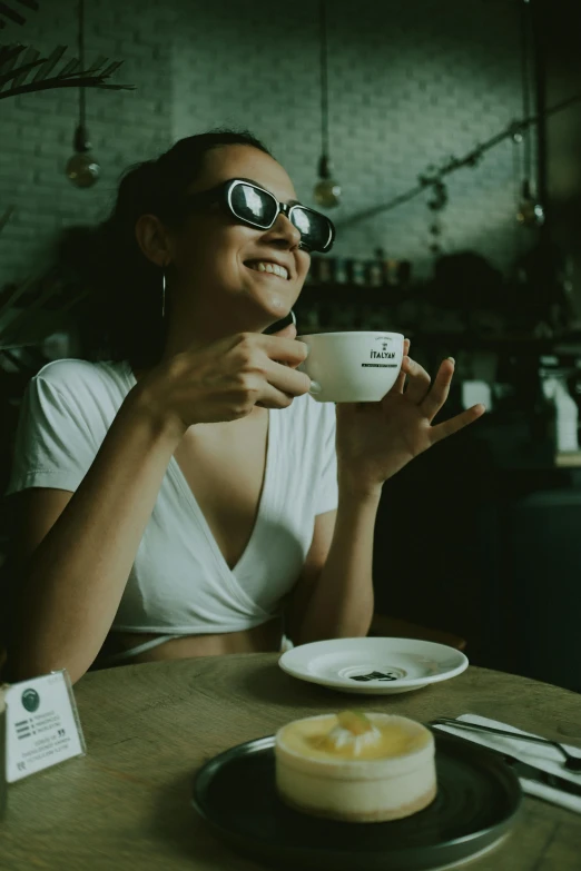 a woman with glasses drinking out of a mug