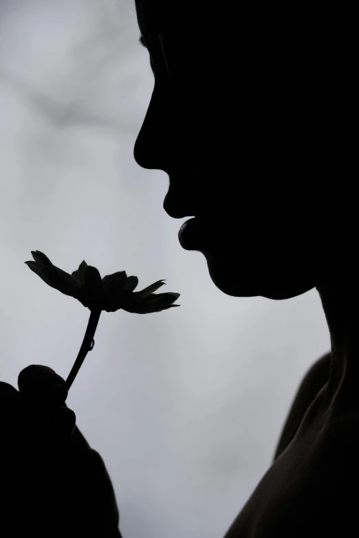 a girl smelling a single flower with one petals