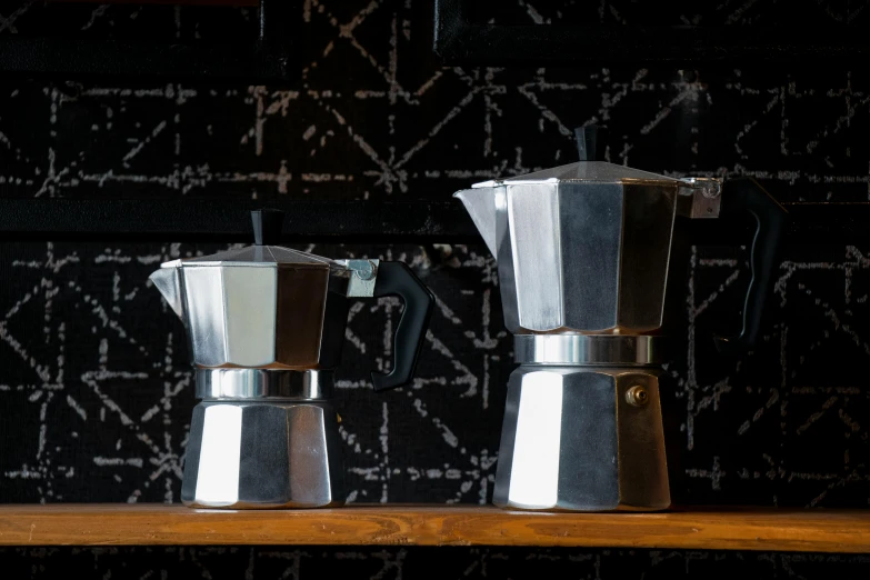 two silver coffee pots on a wooden counter