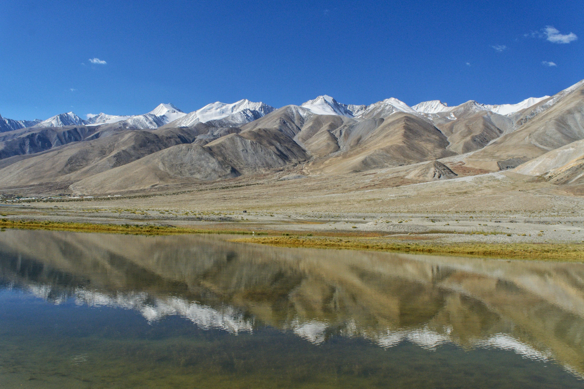 the landscape of the mountain range shows a few small pieces of land and still water