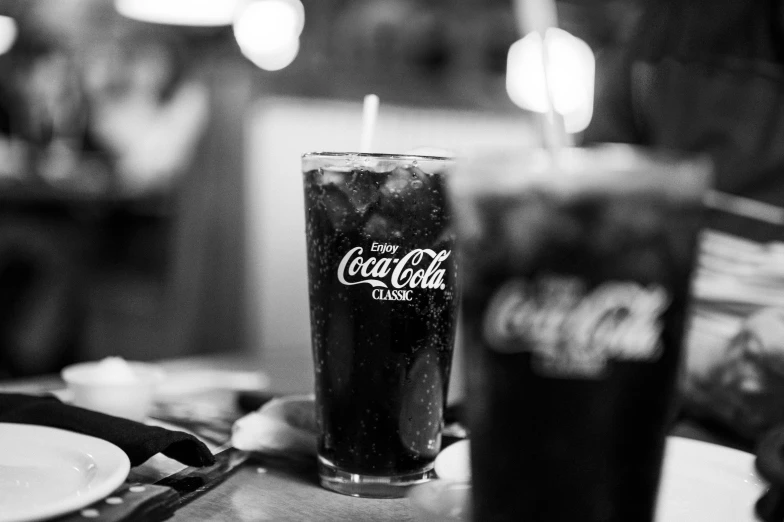 a glass of coke next to two black soda glasses