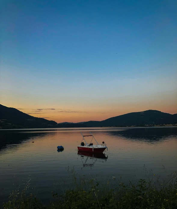 two boats are floating in a lake under a sunset