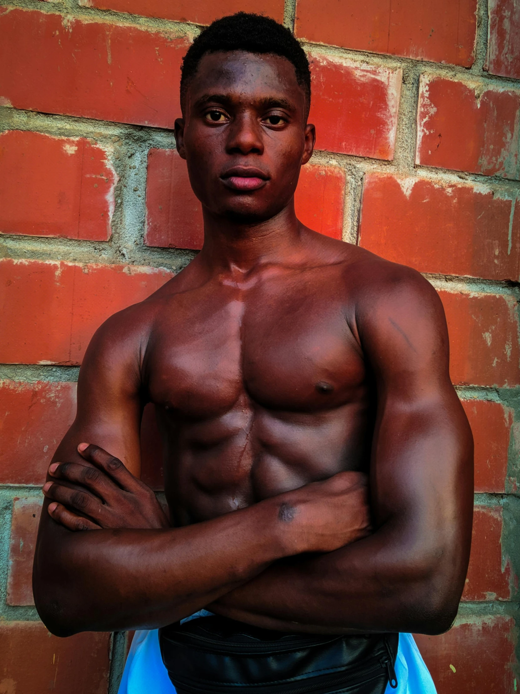 an african american man is posing in front of a brick wall