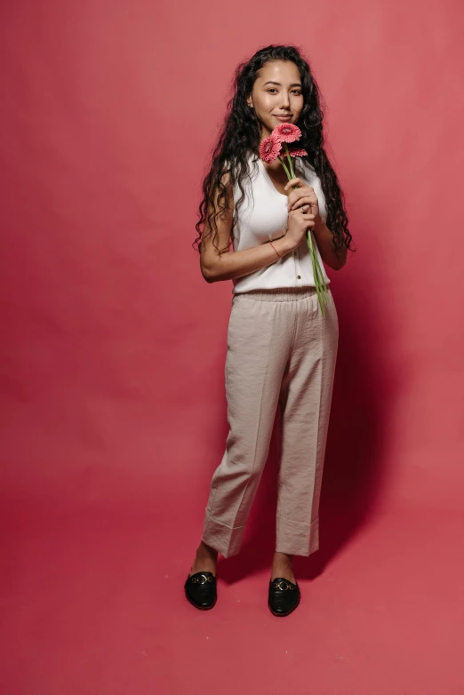 a woman in beige pants holding a flower