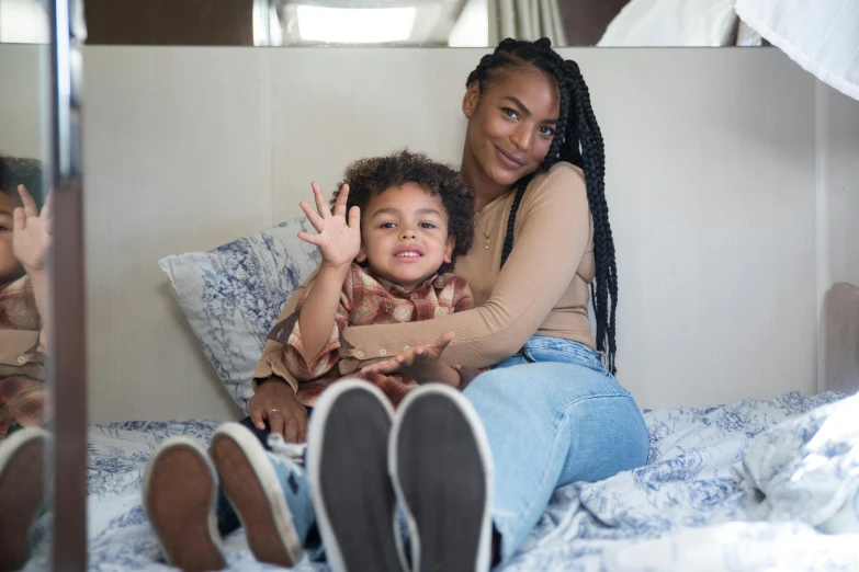 a mother and her daughter in their bed smiling at the camera